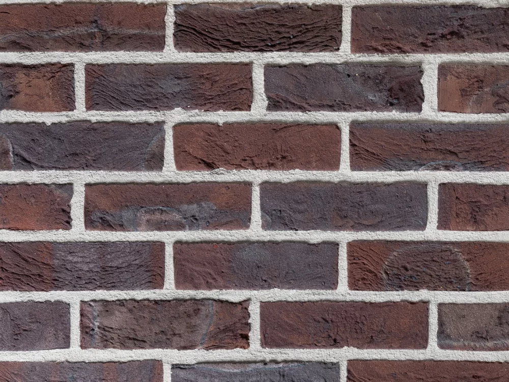 Close-up image of a weathered red brick with purple and brown tones