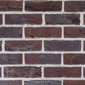 Close-up image of a weathered red brick with purple and brown tones