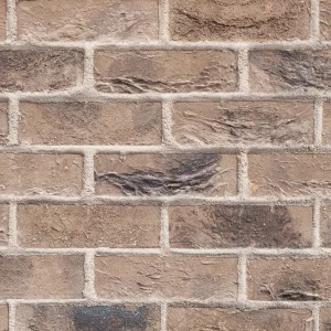 Merino Grey, a brown brick wall featuring horizontal and vertical mortar lines; the bricks show a rough, textured surface with varied colour tones.