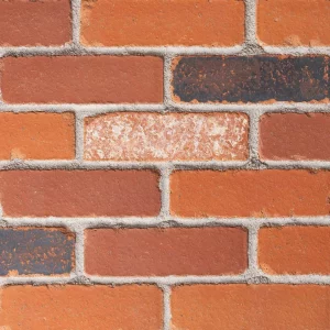 A red brick wall with grey mortar, highlighting the varied shades and textures of the bricks in a horizontal arrangement.