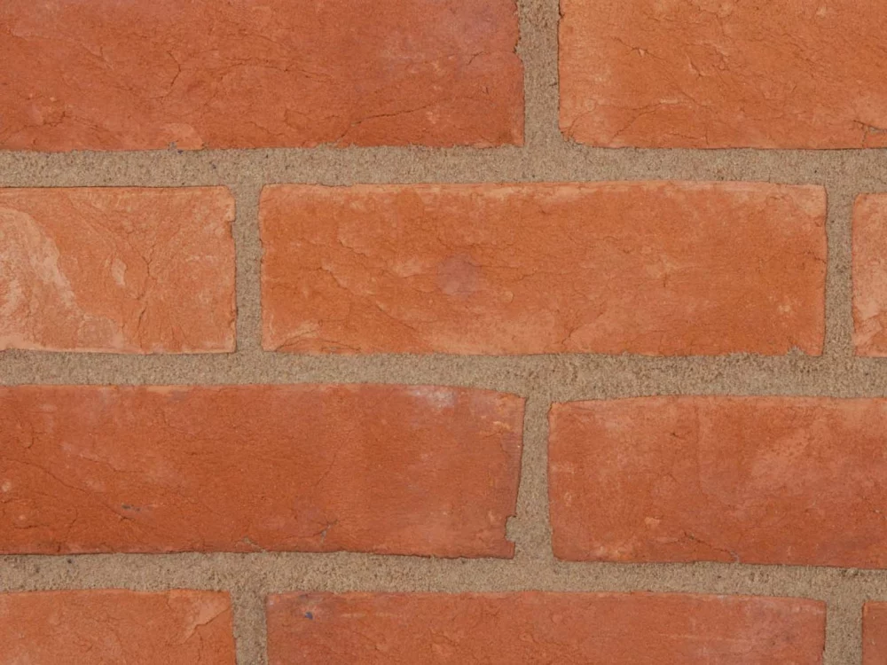A brick wall laid with red bricks and light mortar in a classic stretcher pattern