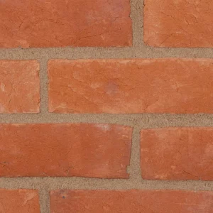 A brick wall laid with red bricks and light mortar in a classic stretcher pattern