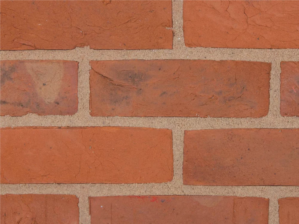 A red brick wall laid in a stretcher pattern and light mortar lines