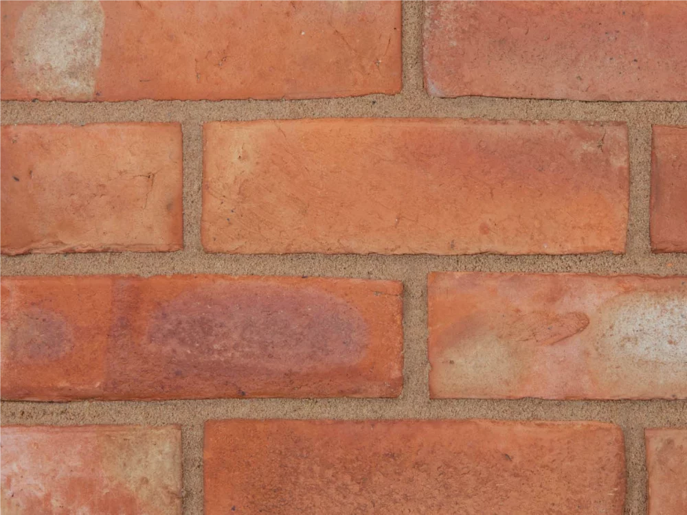 An orange brick with light coloured mortar laid in a traditional pattern