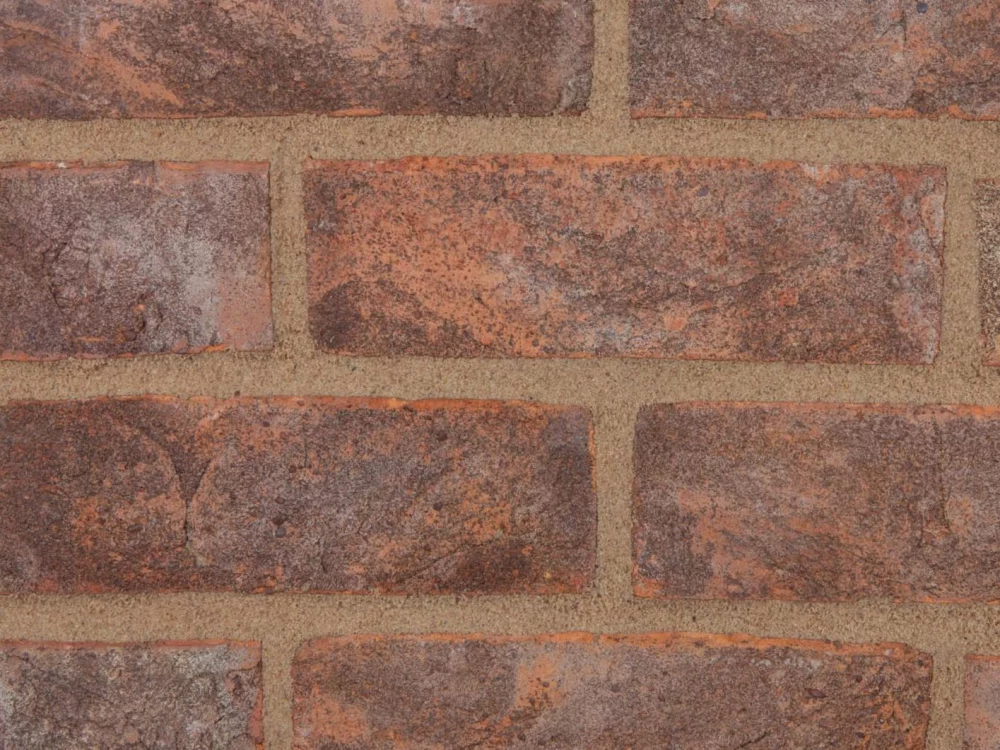 A brick wall showcasing grey and brown bricks laid in a stretcher pattern