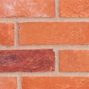 A red and orange brick wall with light mortar laid in a stretcher pattern