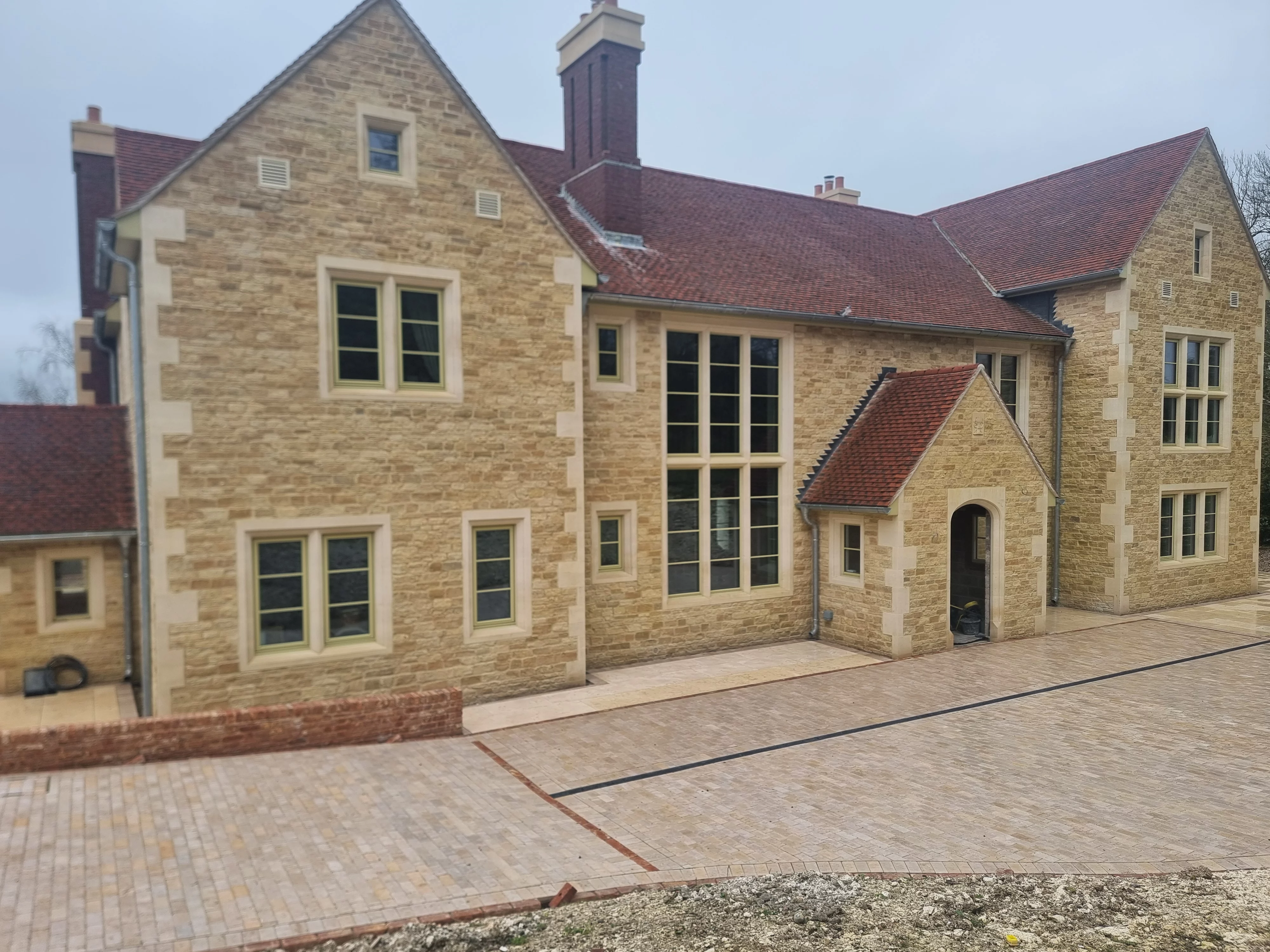 A traditional style property with a natural stone facade featuring stone quoins, many windows with stone surrounds and a red tiled roof