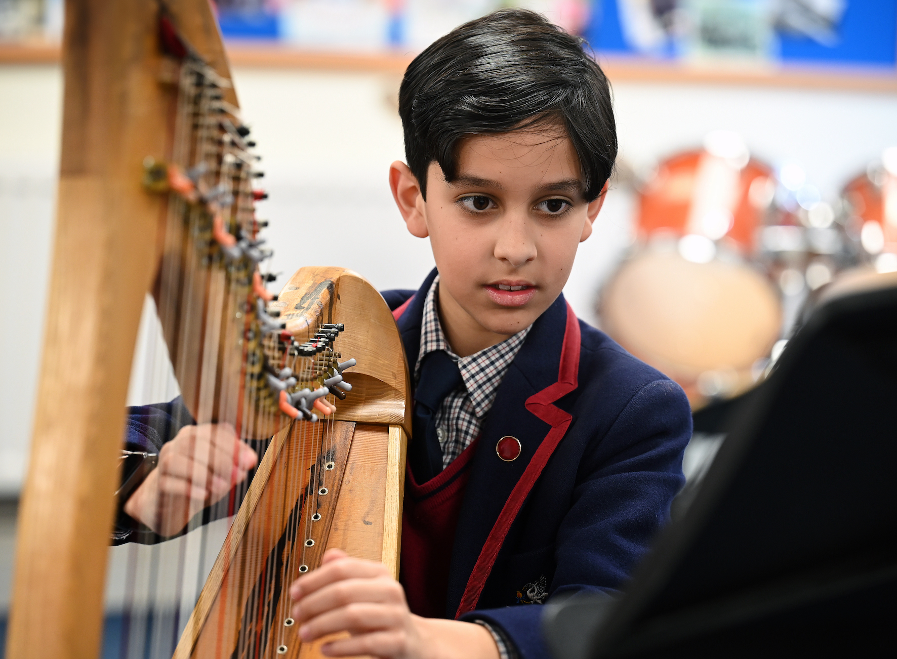 Pupil playing harp in music lesson at Swanbourne House Buckinghamshire