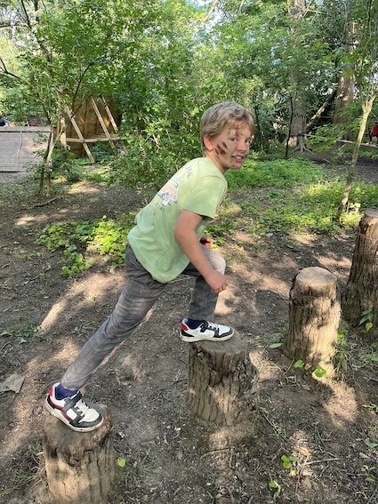 A pupil playing on woodland logs during a Swanbourne House school trip.
