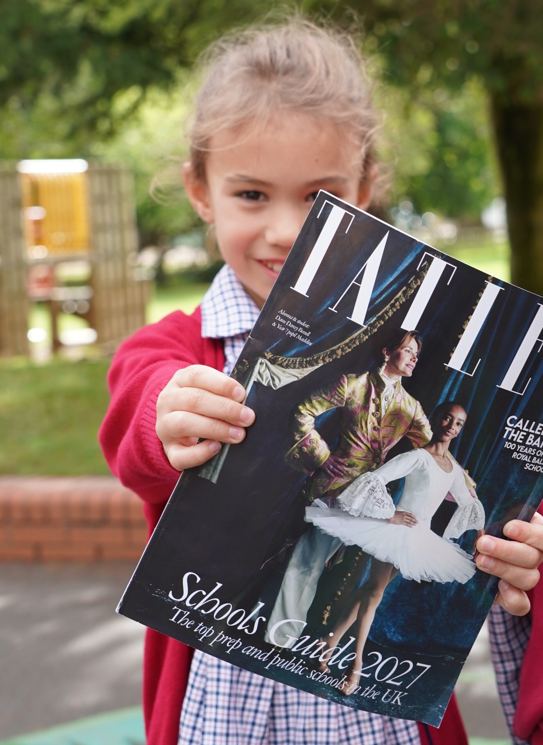 Swanbourne House pupil holding a copy of the Tatler Schools Guide 2027 featuring the School.