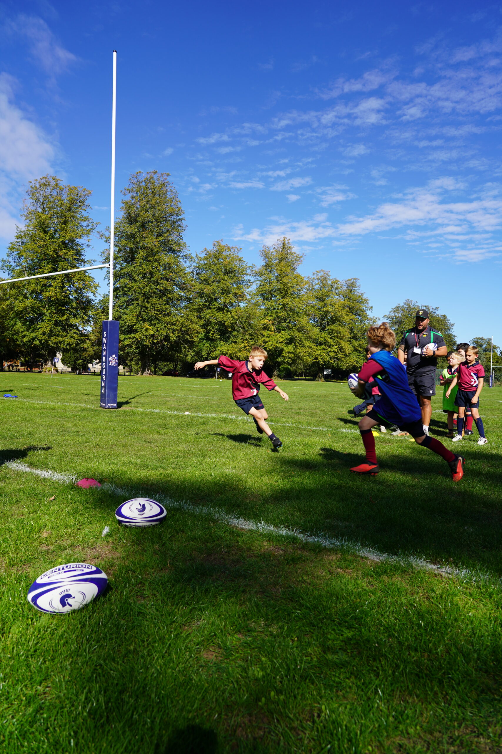 Northampton Saints rugby coach Jake Millburn leading a training session with Swanbourne House pupils during rugby practice.